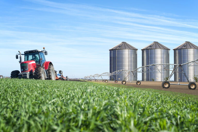 Agriculture and food production concept with tractor machine silos and irrigation system